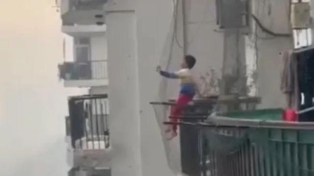 ghaziabad-child-sits-on-high-rise-balcony-grill-with-legs-dangling-internet-demands-stricter-safety-measures-watch